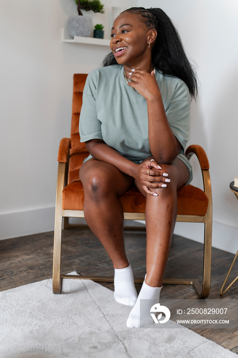 Portrait of young woman sitting in armchair at home