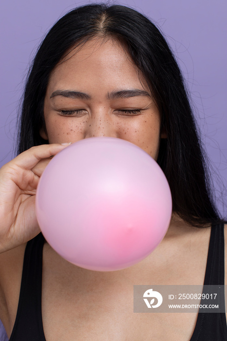 Woman with black hair blowing pink balloon