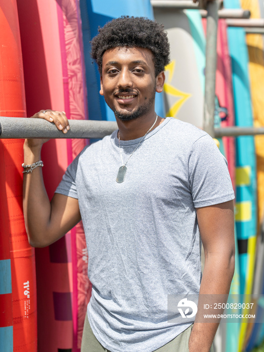 Portrait of smiling man standing next to paddleboard rack