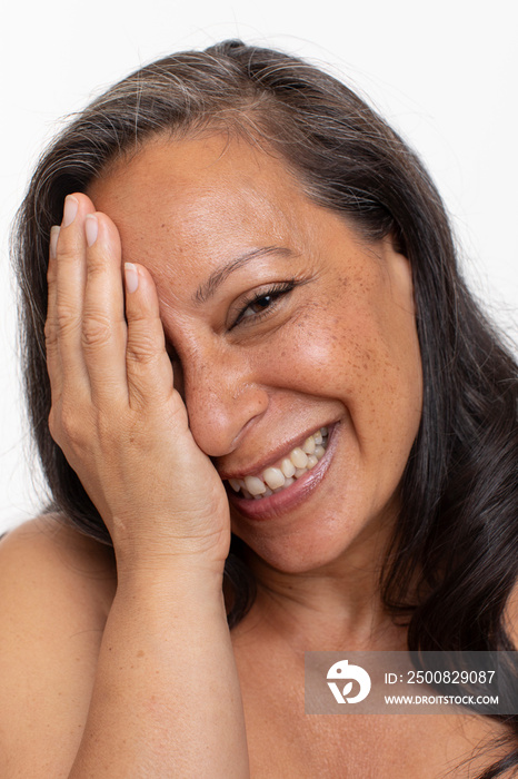 Studio portrait of smiling shirtless woman covering eye