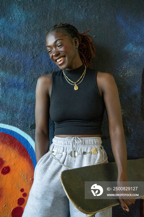 Young female skateboarder laughing outdoors