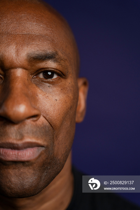 Portrait of serious man looking at camera against purple background