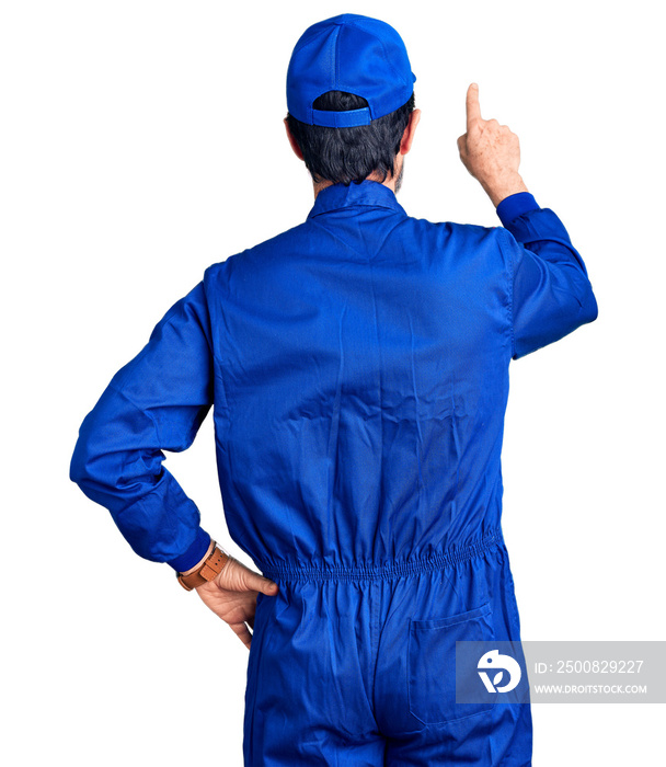 Middle age handsome man wearing mechanic uniform posing backwards pointing ahead with finger hand