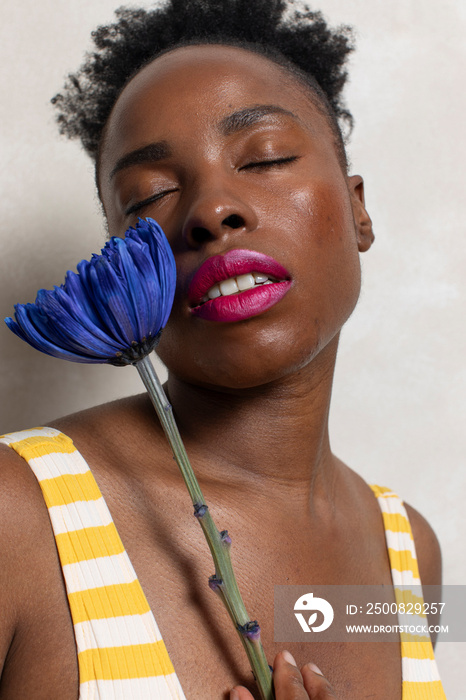 Portrait of woman with closed eyes holding blue flower