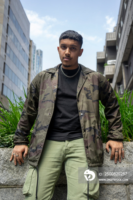 Man wearing camouflage jacket and cargo pants,looking at camera