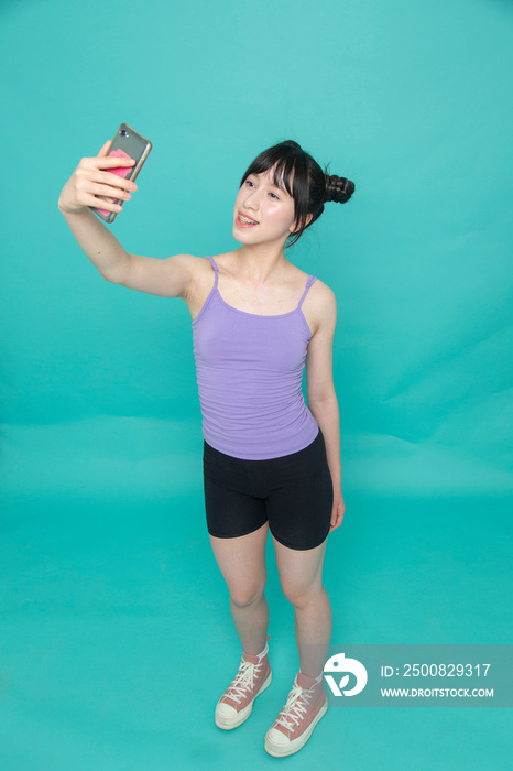 Studio shot of smiling girl taking selfie