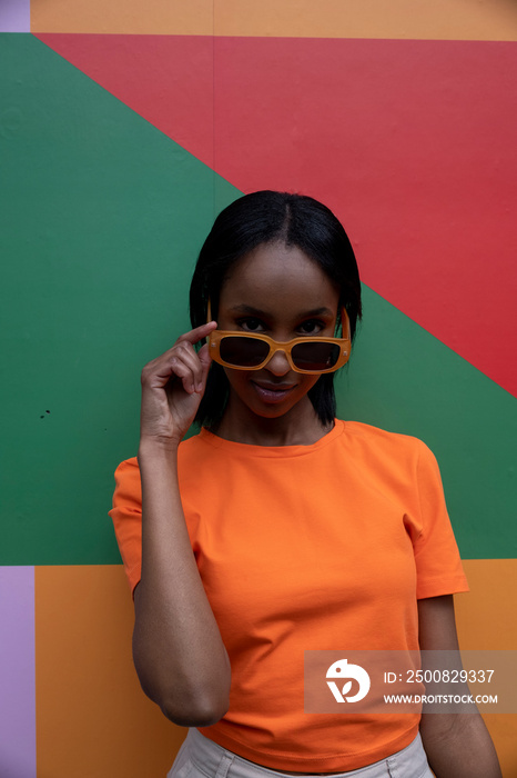 Portrait of smiling young woman in orange sunglasses