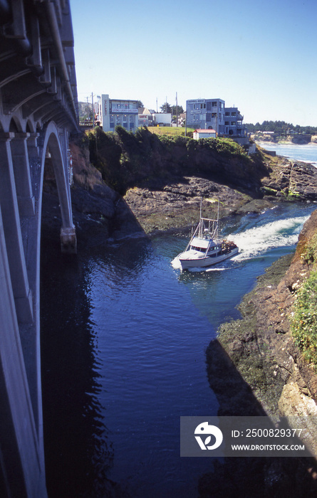 A commercial fishing boat enters Depoe Bay, Oregon under the highway bridge into one of the world’s smallest navigable harbors