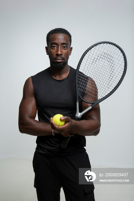 Portrait of man holding tennis ball and racket