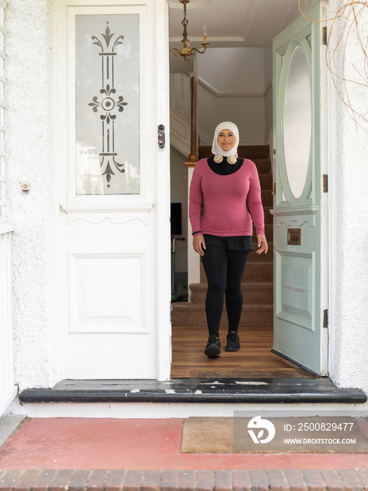 UK,Sutton,Woman in headscarf and sports clothing leaving house