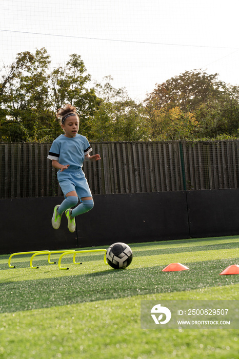 Girl (6-7) practicing on soccer field