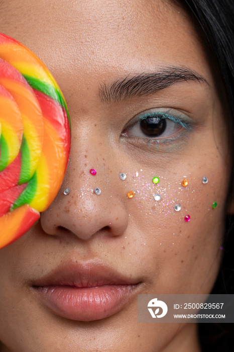 Woman holding colorful lollipop in front of face