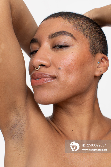 Studio portrait of smiling woman with short hair and nose ring