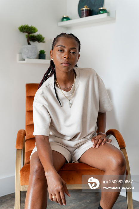 Portrait of beautiful woman looking at camera while sitting in armchair at home