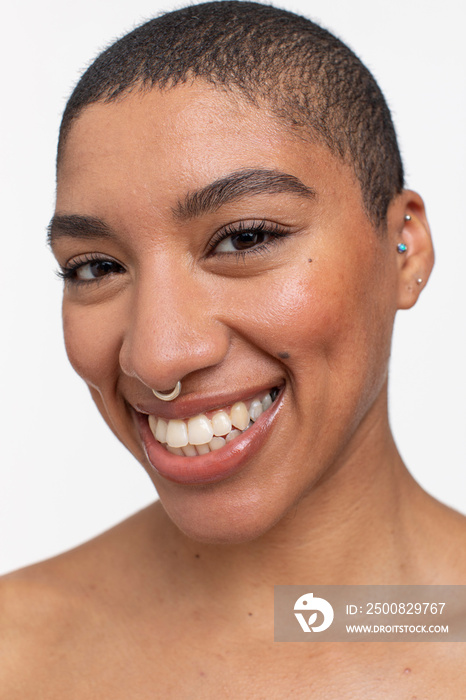 Studio portrait of smiling woman with short hair and nose ring