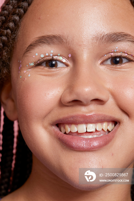 Close-up of smiling girl with decorative stickers on face