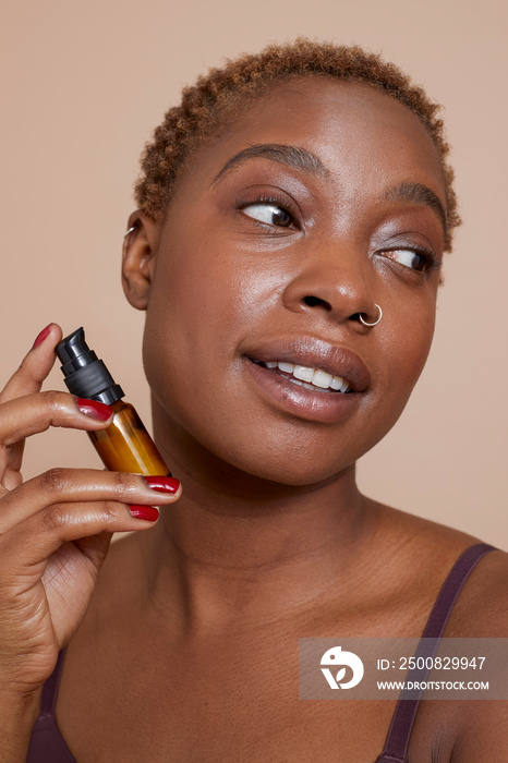 Studio portrait of woman holding face serum