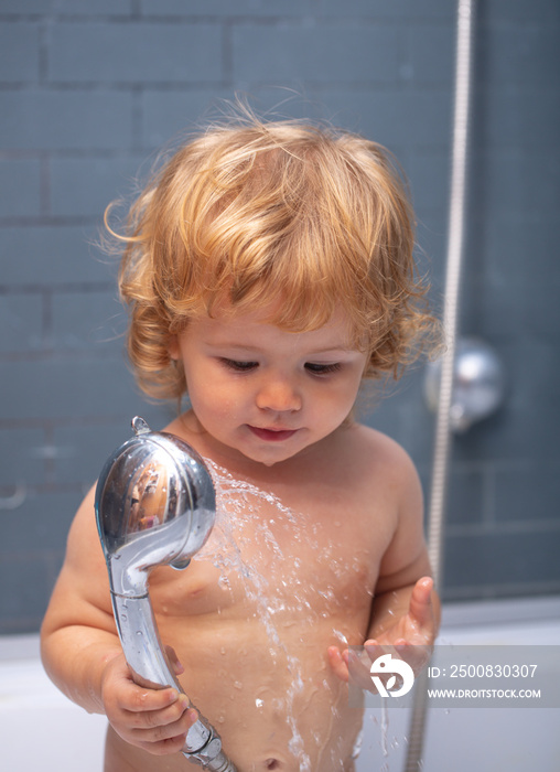 Funny baby kid bathed in foam and washing in bathtub at home.