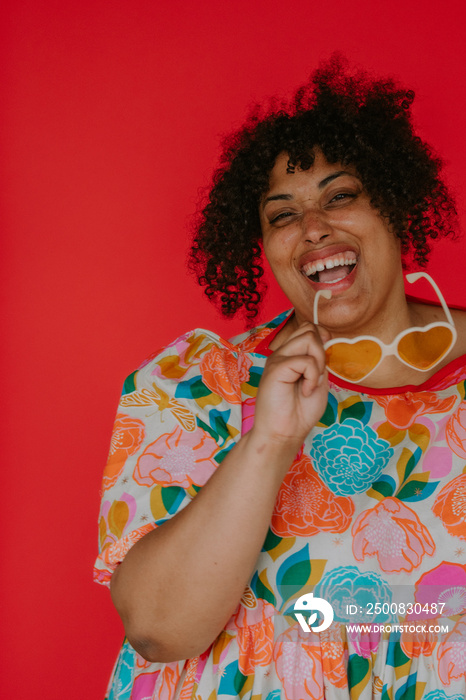 closeup portrait of a plus size black person smiling with heart sunglasses