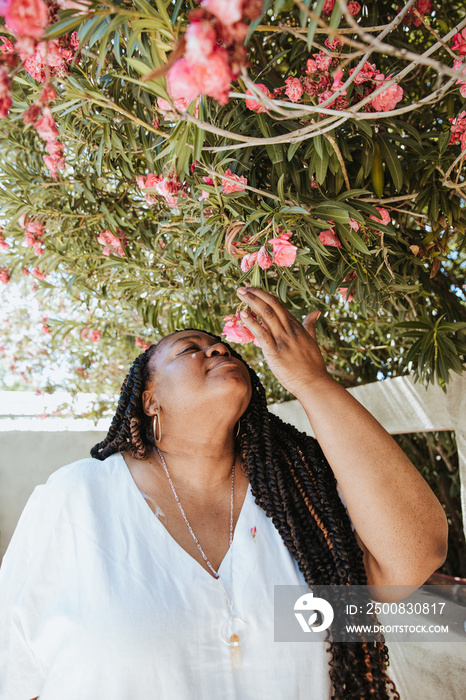 plus size African American woman smelling and looking at pink flowers