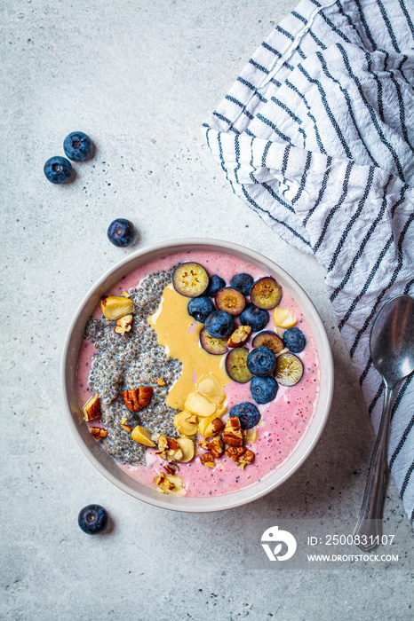 Acai smoothie bowl with chia seeds, berries, nuts and peanut butter, top view. Healthy breakfast concept.