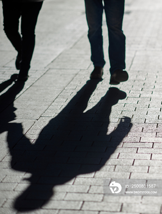 Silhouette and shadow of two people walking on a street