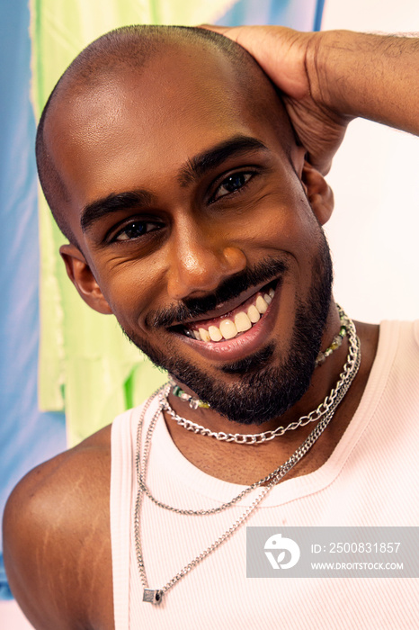 Malaysian Indian man posed in front of a cloth background, styled in a yellow shirt and hat