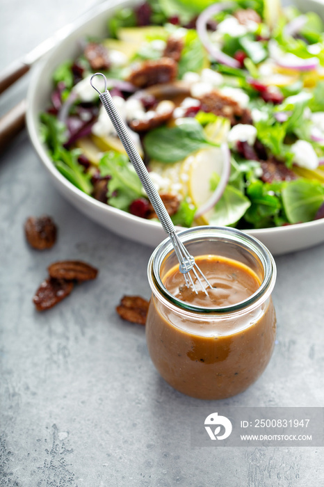 Balsamic vinaigrette dressing for a salad, small glass jar with a whisk