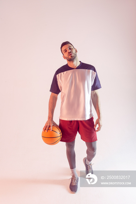 European sportsman with basketball ball in studio