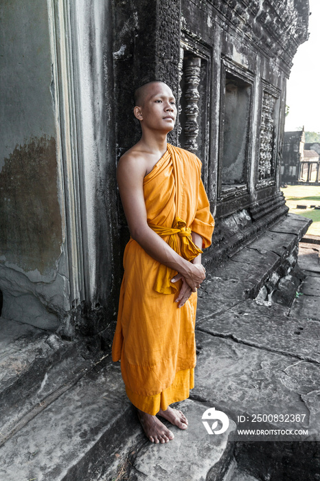 Young buddhist monk standing outside temple in Angkor Wat, Siem Reap, Cambodia