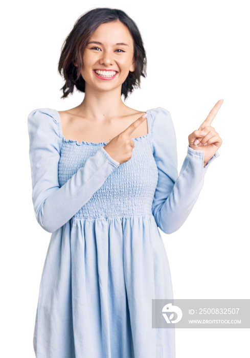 Young beautiful girl wearing casual clothes smiling and looking at the camera pointing with two hands and fingers to the side.