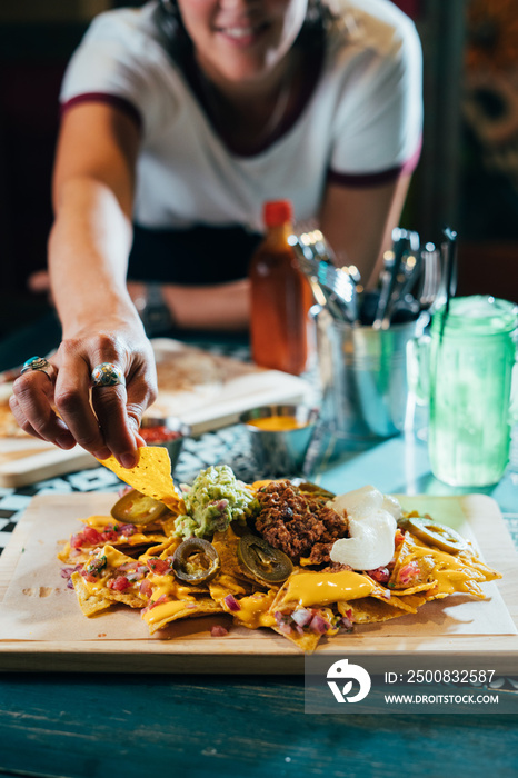 Happy young woman eating street nachos at outdoor mexican restaurant. Mexican food.