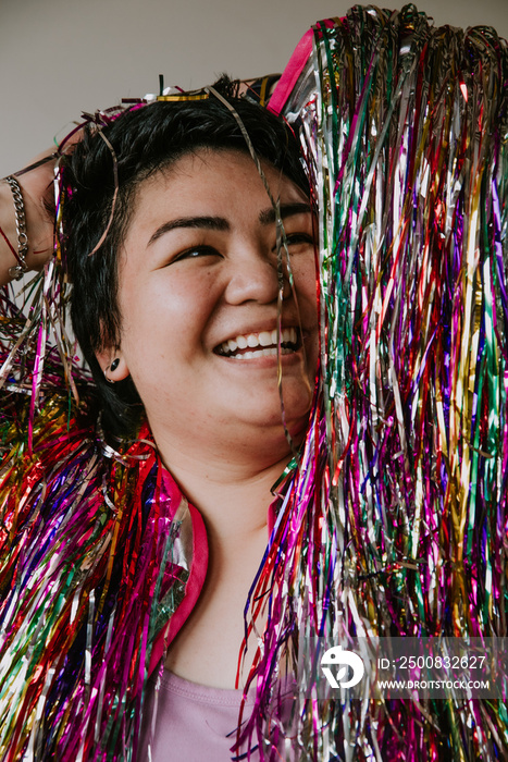 plus size filipino woman smiling surrounded by tinsel