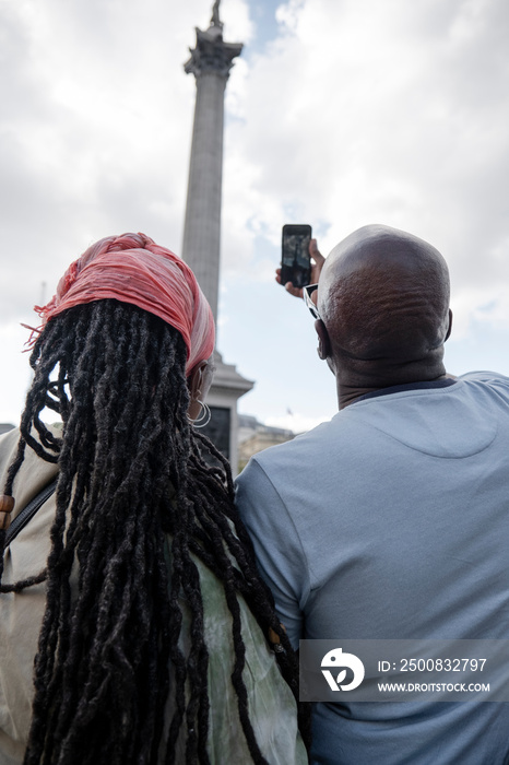 UK, London, Happy mature couple photographing Nelson’s Column while visiting city