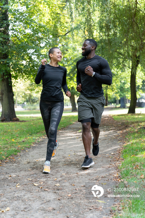 Smiling man and woman jogging in park