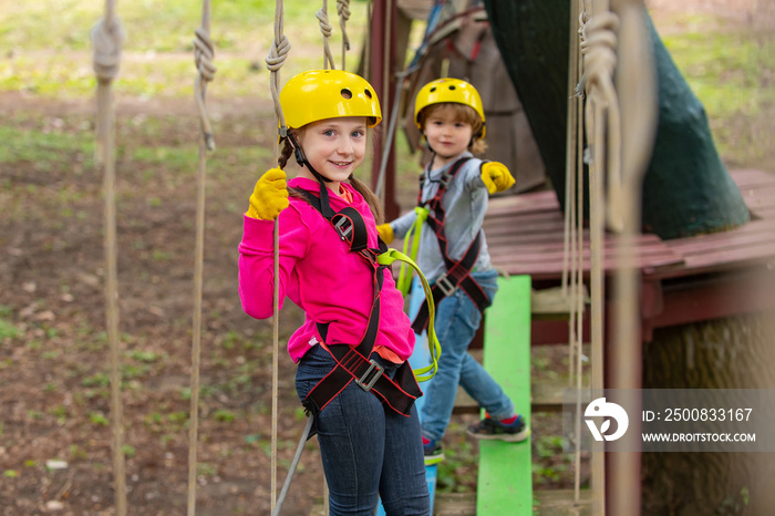 Artworks depict games at eco resort which includes flying fox or spider net. Portrait of a beautiful kid on a rope park among trees. Cargo net climbing and hanging log.