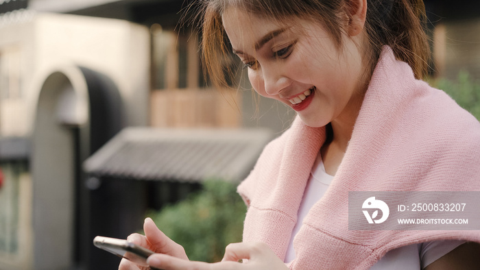 Cheerful Asian backpacker blogger woman using smartphone for direction and looking on location map while traveling at Chinatown in Beijing, China. Lifestyle backpack tourist travel holiday concept.