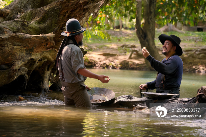 Vintage photo of a cowboy man panning for gold in the river.