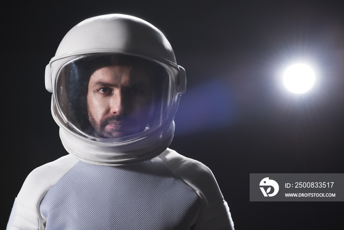 Sense of responsibility. Portrait of serious bearded astronaut wearing helmet and hyperbaric protective costume is standing and looking at camera confidently. Black background with copy space