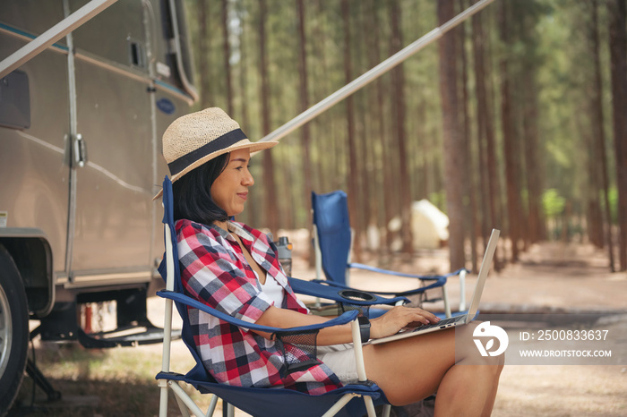 Woman looking at the laptop near the camping . Caravan car Vacation. Family vacation travel, holiday trip in motorhome RV. Wi-fi connection information communication technology.