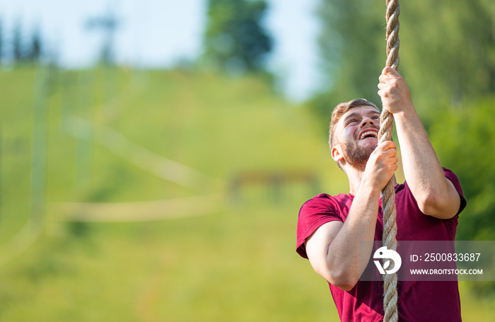 Overcome obstacle using rope during extreme race in the boot camp