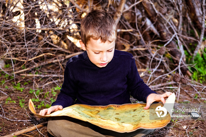 A clever boy searches an ancient map for something buried in a forest.