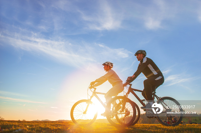 Happy mountainbike couple outdoors have fun together on a summer afternoon sunset