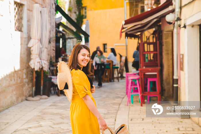 tourist woman in yellow sundress walking by small croatian city street