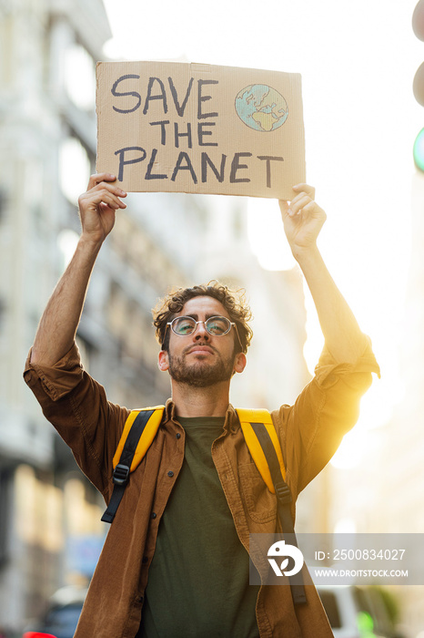 Activist in the city with a sign that says SAVE THE PLANET.