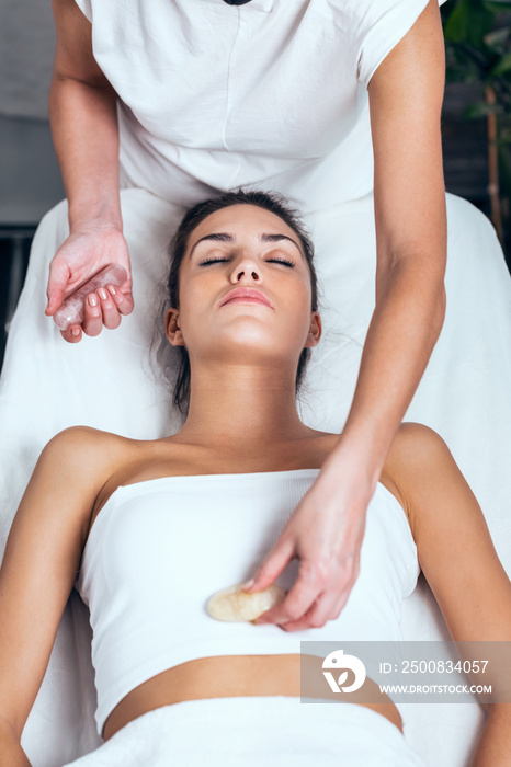 Beautiful young woman having reiki healing treatment in health spa center