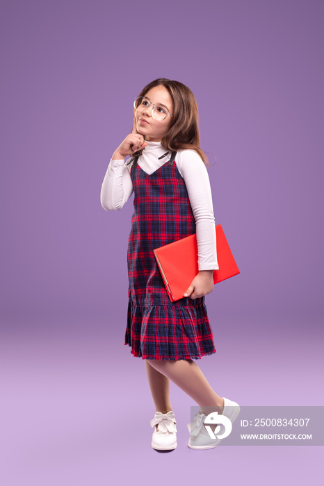 Smart schoolgirl in uniform holding book