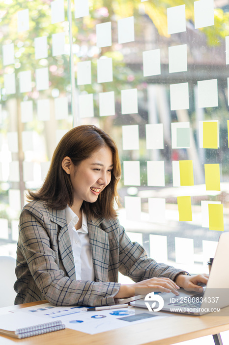 Beautiful smiling asian female accountant working on laptop computer in financial accounting analysis report and modern tax system. vertical image