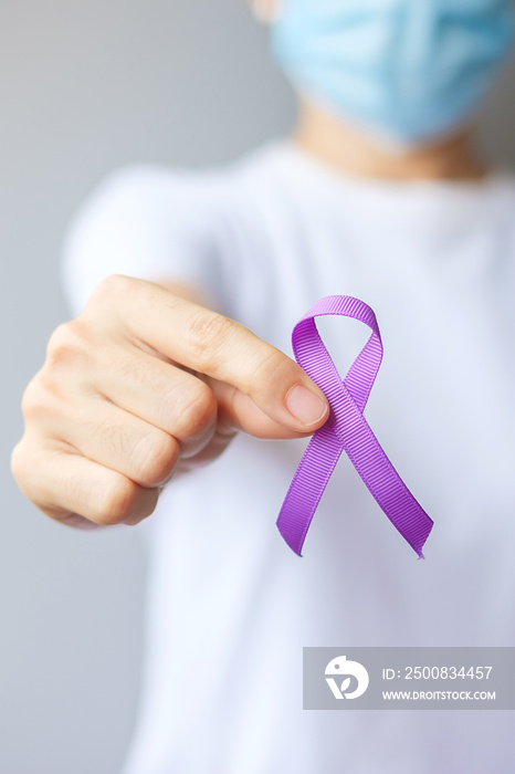 Hand holding purple Ribbon for Pancreatic, Esophageal, Testicular cancer, world Alzheimer, epilepsy, lupus, Sarcoidosis, Fibromyalgia and domestic violence Awareness month. World cancer day concept