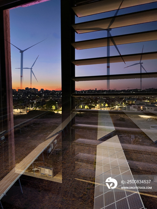 Multiple exposure of windmills and solar panels for electric power with city in evening